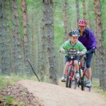 two people cycling through a forest