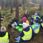 Group leader talking to a group of kids in a forest