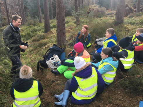 Group leader talking to a group of kids in a forest