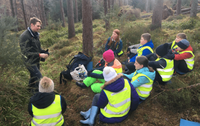 Group leader talking to a group of kids in a forest