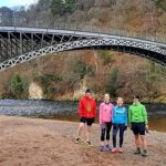 group of runners next to a bridge