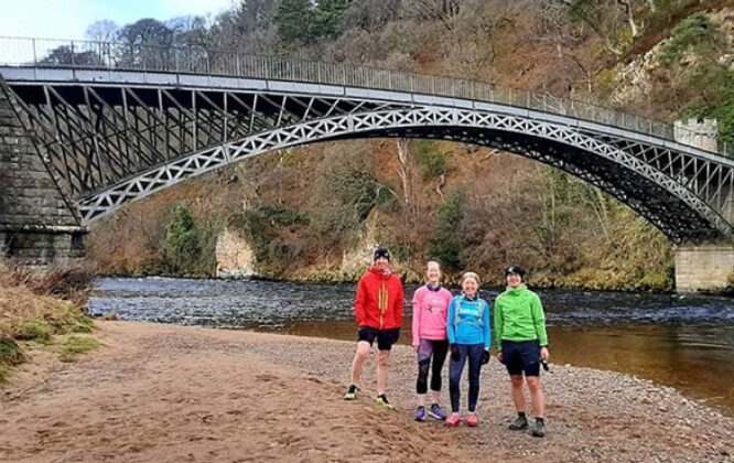 group of runners next to a bridge