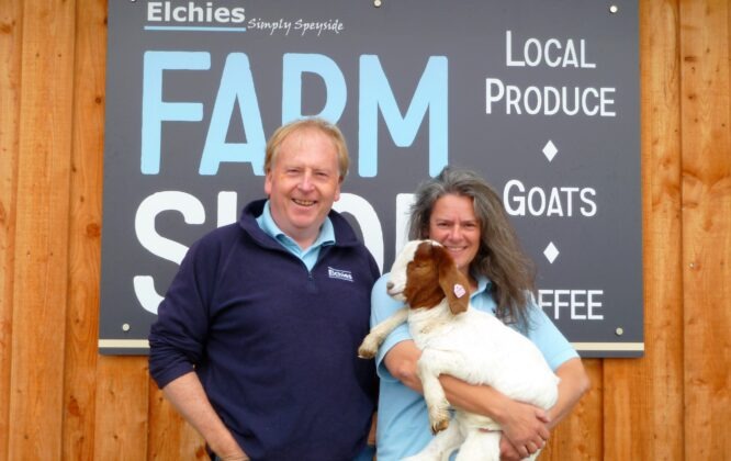 Two people holding a lamb