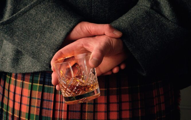 Man in kilt holding whisky glass