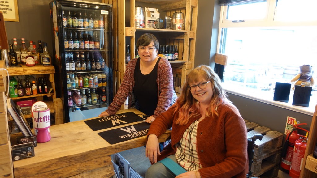 Two ladies stand at a bar in Windswept Brewing