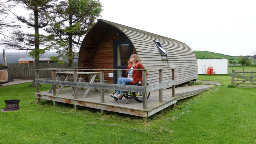 Lady in a wheelchair on an accessible ramp leading to glamping pod